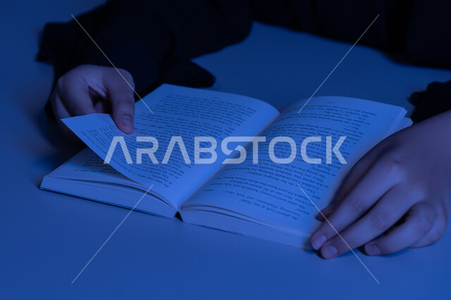 الاستمتاع بالأنشطة الترفيهية المفيدة في وقت الفراغ، مفهوم الثقافة والتعلم الذاتي, شابة سعودية تقوم بقراءة القصص والروايات الممتعة, صورة مقربة لأيدي امرأة عربية خليجية اماراتية ترتدي العباءة تقوم بممارسة هواية المطالعة