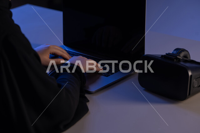 محاكاة العالم الخيالي, استخدام الأجهزة التكنولوجية والتقنيات الحديثة, صورة مقربة لايدي امرأة عربية خليجية اماراتية تقوم بإنجاز العمل على جهاز الحاسوب المحمول وبجانبها نظارة الفي ار, شابة سعودية تقوم بالنقرعلى لوحة المفاتيح