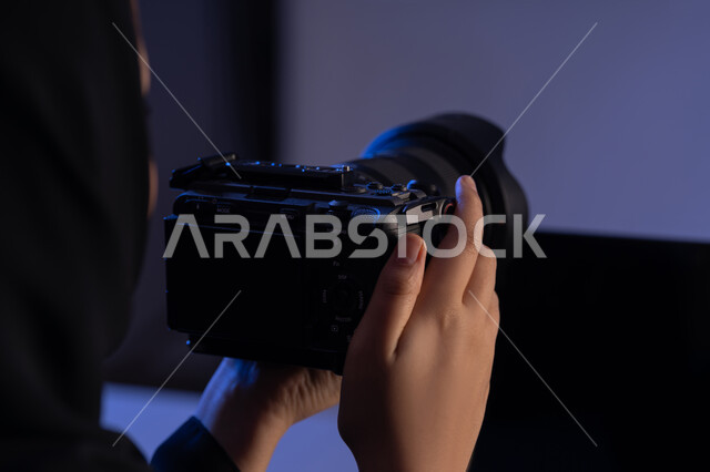 استخدام التقنيات الحديثة المتطورة، ممارسة الهواية المفضلة بشغف، احتراف واتقان مهنة التصوير، صورة مقربة من الجانب لامرأة عربية خليجية اماراتية محجبة ترتدي العباءة تحمل بيدها كاميرا فوتوغرافية، شابة سعودية تقوم بالتقاط الصور التذكارية