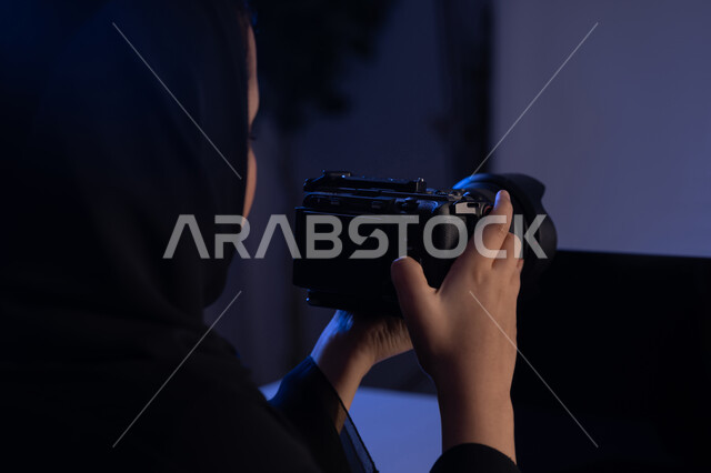 ممارسة الهواية المفضلة بشغف، احتراف واتقان مهنة التصوير، صورة مقربة من الجانب لامرأة عربية خليجية اماراتية محجبة ترتدي العباءة تحمل بيدها كاميرا فوتوغرافية، استخدام التقنيات الحديثة المتطورة، شابة سعودية تقوم بالتقاط الصور التذكارية