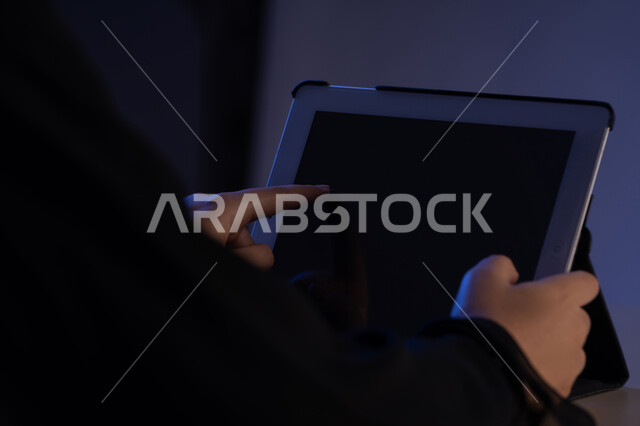 استحدام الاجهزة التقنية الحديثة والمتطورة، عرض شاشة سوداء فارغة، متابعة الدروس التعليمية، تصفح مواقع التواصل الاجتماعي، صورة مقربة لايدي امرأة عربية خليجية إماراتية تقوم بإنجاز المهام المطلوبة عن بعد، شابة سعودية تستعمل جهاز الآيباد