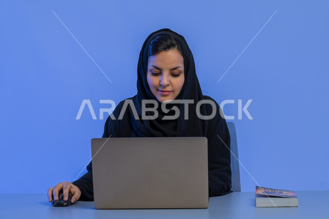 Office administrative jobs and professions, integrating modern technology into practical life, data entry concept, close-up portrait of an Arab Gulf Emirati woman working on a laptop, a young Saudi woman sitting in front of a desk, blue background