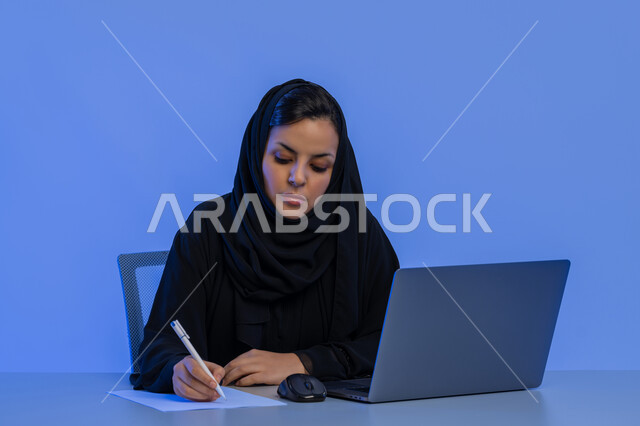 مهن ووظائف إدارية مكتبية، بورتريه مقرب لامرأة عربية خليجية اماراتية تستخدم الحاسوب المحمول، شابة سعودية تقوم بكتابة وتدوين الملاحظات والمعلومات، إدارة الأعمال وتنظيمها، دمج التكنولوجيا الحديثة بالحياة العملية