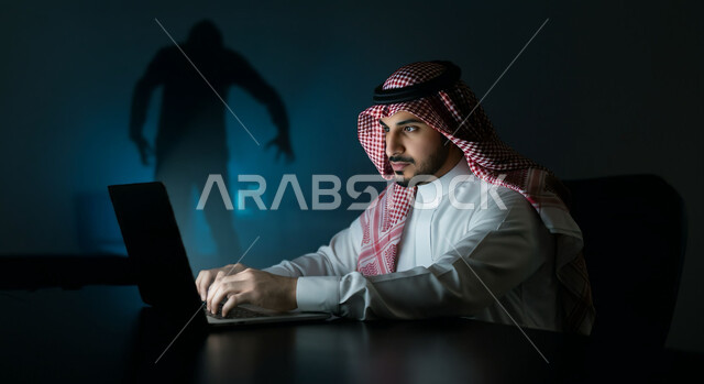 التعرض للهجوم التقني, صورة مقربة لرجل عربي خليجي سعودي يرتدي الثوب التقليدي والشماغ يستخدم الحاسب المحمول, اختراق حماية وأمن وخصوصية المستخدمين, مفهوم الحفاظ على نظام الأمن الالكتروني, خلفية رجل هاكر ملثم