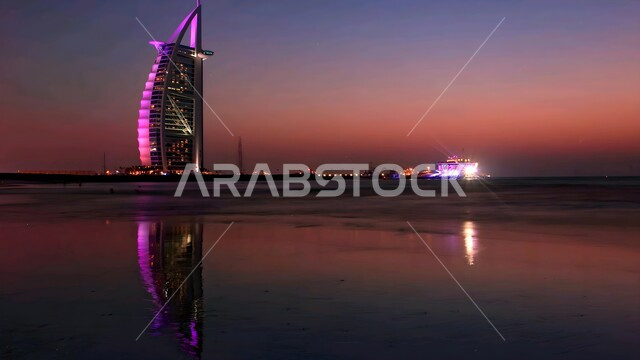 أماكن جذب السياح من شتى أنحاء العالم، النمو والتقدم العمراني للأبراج وناطحات السحاب المطلة على البحر في الإمارات العربية المتحدة، برج العرب في إمارة دبي وقت الغروب، الواجهة البحرية على ساحل الخليج العربي, الفن الهندسي المعماري لبناء الفنادق والمنتجعات السياحية