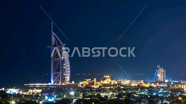 الواجهة البحرية على ساحل الخليج العربي, النمو والتقدم العمراني للأبراج وناطحات السحاب المطلة على البحر في الإمارات العربية المتحدة، برج العرب في إمارة دبي في الليل، أماكن جذب السياح من شتى أنحاء العالم، الفن الهندسي المعماري لبناء الفنادق والمنتجعات السياحية