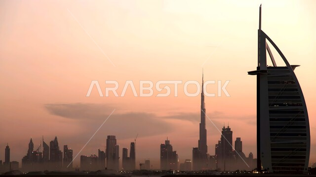 أماكن جذب السياح من شتى أنحاء العالم، الواجهة البحرية على ساحل الخليج العربي, النمو والتقدم العمراني للأبراج وناطحات السحاب المطلة على البحر في الإمارات العربية المتحدة، برج العرب في إمارة دبي وقت الغروب، الفن الهندسي المعماري لبناء الفنادق والمنتجعات السياحية