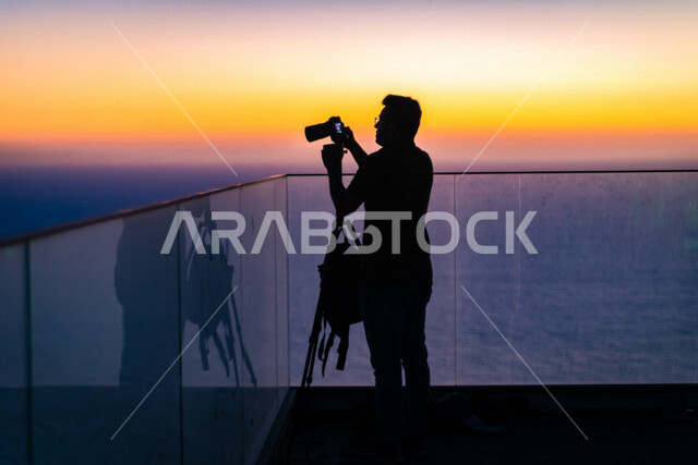 صورة إبداعية ظلية لرجل يقف أمام البحر ، الواجهة البحرية وقت الغروب ، ألوان الغروب الجميلة ، غروب الشمس على الواجهة البحرية ، صورة ظلية جميلة 