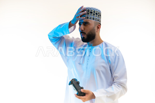 Modern entertainment electronic devices and technologies, having a fun and entertaining time, interacting and merging with video games, portrait of a young Gulf Arab Omani man wearing a dishdasha and a turban pressing the joystick buttons, full body image, white background