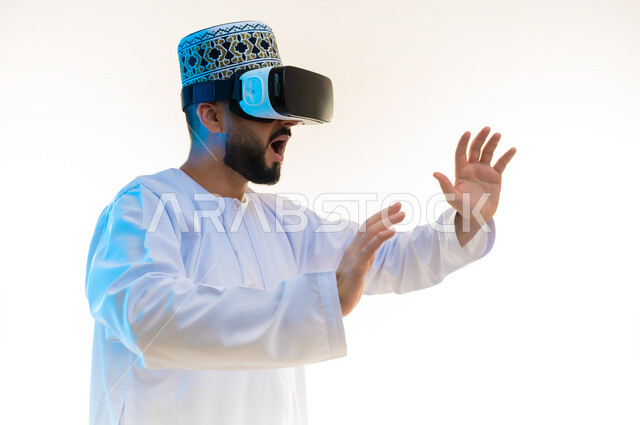 محاكاة العالم الخيالي, بورتريه مقرب من الجانب لرجل عربي خليجي عماني يرتدي الدشداشة والكمة يضع نظارة ثلاثية الأبعاد يتفاعل معها، رفع اليدين بإيماءات الصدمة والاندهاش، مشاهدة الأفلام باستخدام تقنيات الواقع الافتراضي, محاولة تجنب شيء ما، خلفية بيضاء