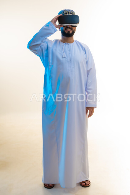 التطور التقني والتكنولوجي, الاندماج ومحاكاة العالم الخيالي, بورتريه لرجل عربي خليجي عماني يرتدي الدشداشة والكمة ونظارة ثلاثية الأبعاد، قضاء أوقات ممتعة بمشاهدة الأفلام باستخدام تقنيات الواقع الافتراضي, الجسم بالطول الكامل، خلفية بيضاء
