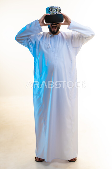 الاندماج ومحاكاة العالم الخيالي, مشاهدة أفلام الرعب باستخدام تقنيات الواقع الافتراضي, فتح الفم بإيماءات الصدمة والاندهاش، بورتريه لرجل عربي خليجي عماني يرتدي الدشداشة والكمة ونظارة ثلاثية الأبعاد، الجسم بالطول الكامل، خلفية بيضاء