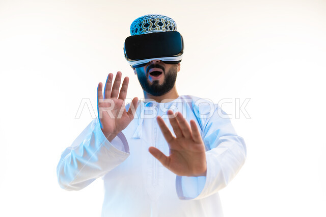 رفع اليدين بإيماءات الصدمة والاندهاش، محاولة تجنب شيء ما، محاكاة العالم الخيالي, بورتريه مقرب لرجل عربي خليجي عماني يرتدي الدشداشة والكمة يضع نظارة ثلاثية الأبعاد يقوم بالتفاعل معها، مشاهدة الأفلام باستخدام تقنيات الواقع الافتراضي, خلفية بيضاء