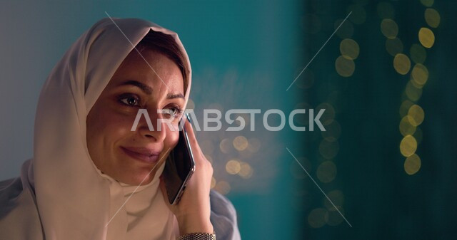 سيدة عربية في المنزل ، تقوم بإجراء مكالمة هاتفية بإستخدام الهاتف المحمول، العمل عن بعد، مفهوم إستخدام التكنلوجيا وأجهزة التقنية الحديثة، التسلية والترفيه، حجز طلبات الأونلاين ، التسويق الإلكتروني، عقد صفقات عبر الجوال