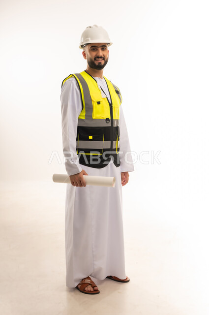 Concept of architectural construction and engineering, portrait of an Arab Gulf Omani engineer wearing a dishdasha, helmet and protective vest holding a blueprint looking at the camera with gestures of confidence and pleasure, following up on the progress of construction projects, youth professions and jobs, full-length body image, white background