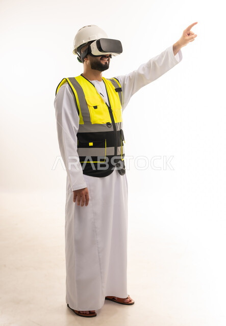 التفاعل مع الهندسة الافتراضية، بورتريه لمهندس عربي خليجي عماني يرتدي الدشداشة والسترة الخاصة بالعمل ونظارة الواقع الافتراضي يرفع إصبع السبابة للمس عناصر هولوجرامية، رؤية مستقبلية 2030، دمج التكنولوجيا بالمجالات الهندسية، الجسم بالطول الكامل، خلفية بيضاء