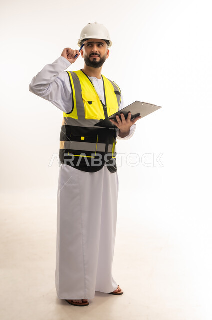 التأكد من سير العمل بالشكل المطلوب والصحيح، إدارة الأعمال والاطلاع على آخر المستجدات، تدوين وتسجيل الملاحظات الهامة، بورتريه لمهندس عربي خليجي عماني يرتدي الدشداشة والسترة وخوذة الحماية يمسك ملف بيده ويفكر بإيماءات التركيز، الجسم بالطول الكامل، خلفية بيضاء