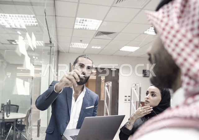 فريق عمل عرب سعوديون خليجيون في مقر العمل, تدوين الملاحظات والمهام على الورق، مناقشة و تحديد الاهداف، استخدام جهاز اللابتوب، أساتذه في الجامعه, مناقشة مشروع, التعليم الجامعي, مدربين جامعيين, وحدة العمل الجماعي