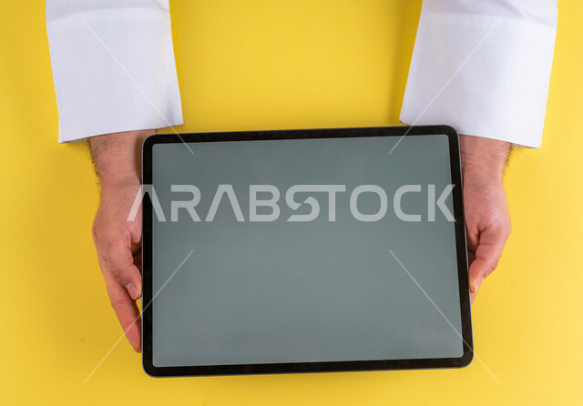 صورة مقربة ليد رجل عربي خليجي سعودي يستخدم جهاز التابلت، الاستمتاع بمشاهدة الافلام ، لعب الالعاب الالكترونية ، متابعة الدروس التعليمية ،استخدام التقنيات الحديثة