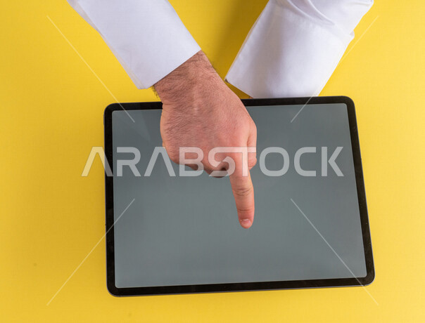 صورة مقربة ليد رجل عربي خليجي سعودي ينقر على شاشة جهاز التابلت، شرح خطوات العمل ،القيام بعمليات التسويق الالكتروني ، التجارة الالكترونية ،تصفح المواقع الالكترونية ، استخدام الاجهزة التقنية الحديثة في الاعمال الادارية