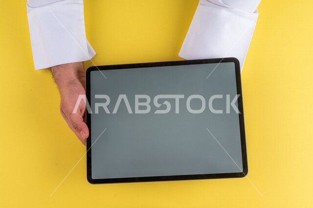 صورة مقربة ليد رجل عربي خليجي سعودي يستخدم جهاز التابلت، الاستمتاع بمشاهدة الافلام ، لعب الالعاب الالكترونية ، متابعة الدروس التعليمية ،استخدام التقنيات الحديثة