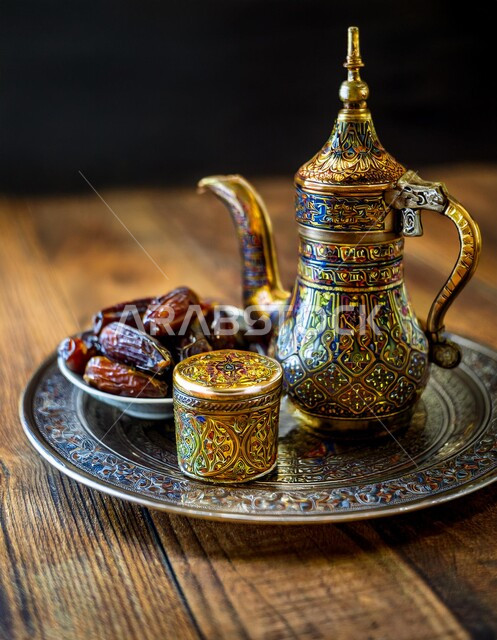  أصالة العادات والتقاليد الأصيلة, الاستمتاع بالمشروبات الساخنة، منتجات محلية وطنية، كرم الضيافة وحسن الاستقبال في المملكة العربية السعودية, طبق من التمر الخليجي الشهي بجانب دلة نحاسية مزخرفة من القهوة العربية