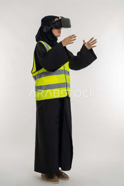 Expressions of holding an item, interacting with virtual engineering, developing engineering fields through VR glasses, side portrait of an Arab Gulf Emirati female engineer wearing a protective jacket and helmet, wearing virtual reality glasses, a young Saudi woman raising her hands with scaling gestures, full body image, white background