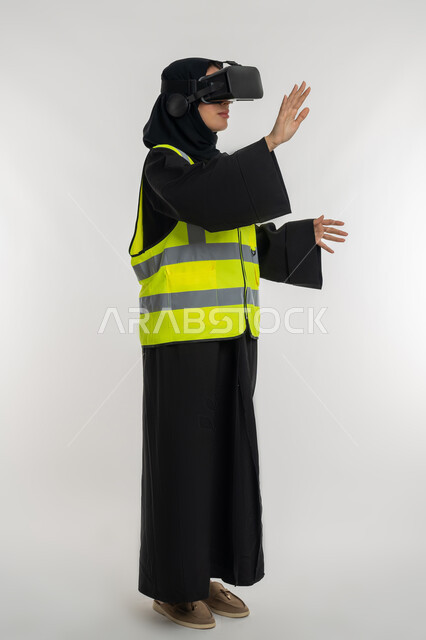 Developing engineering fields through VR glasses, interacting with virtual engineering, side portrait of an Arab Gulf Emirati female engineer wearing a protective jacket and helmet, wearing virtual reality glasses, a young Saudi woman raising her hands with gestures of integration, full body image, white background