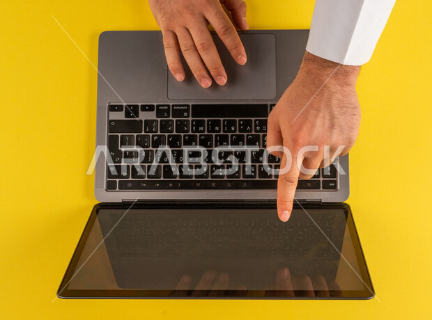 صورة مقربة ليد رجل عربي خليجي سعودي يستخدم الحاسوب المحمول ، مدخل بيانات، القيام بالعمليات الادارية ، متابعة الدروس الالكترونية ، التعليم عن بعد ، الشراء من المواقع الالكترونية ،استخدام الاجهزة التقنية الحديثة في الاعمال الالكترونية