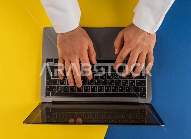 صورة مقربة ليد رجل عربي خليجي سعودي يستخدم الحاسوب المحمول ،مدخل بيانات، الكتابة من خلال لوحة المفاتيح ، التسويق والترويج للمواقع الالكترونية، التعليم عن بعد ، استخدام الاجهزة التقنية الحديثة في الاعمال الادارية