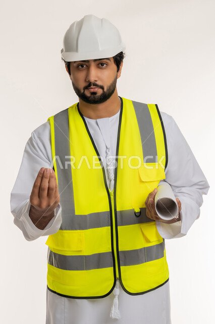 مفهوم الصبر والتريث، العمل في القطاع الهندسي، المهن والوظائف الشبابية في الإمارات، متابعة سير المشاريع الإعمارية، بورتريه لمهندس عربي خليجي إماراتي يرتدي الكندورة والخوذة وسترة الحماية يحمل مخطط هندسي يرفع يده بإيماءات طلب الهدوء والانتظار، خلفية بيضاء