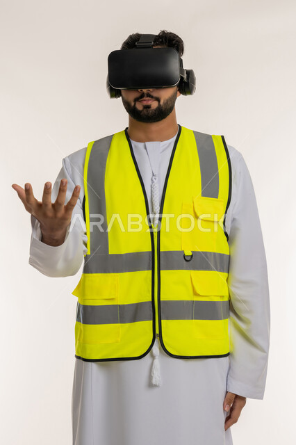 التفاعل مع الهندسة الافتراضية، تطور المجال الهندسي في الإمارات، بورتريه لمهندس عربي خليجي إماراتي يرتدي الكندورة والسترة الخاصة بالعمل ونظارة الواقع الافتراضي يقوم بحمل عنصر هولوجرامي، مشاهدة المشاريع الهندسية بالاعتماد على التكنولوجيا، خلفية بيضاء