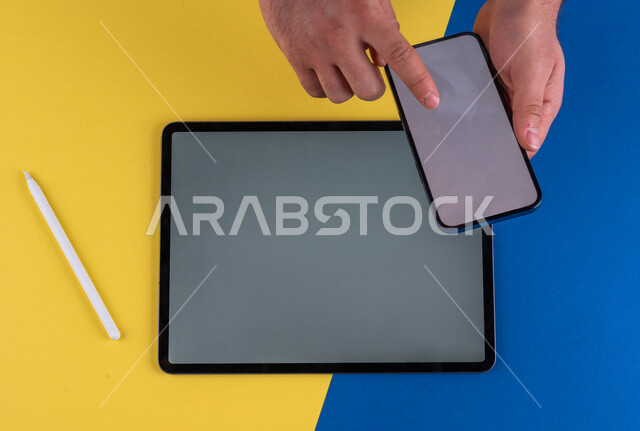 صورة مقربة ليد رجل عربي خليجي سعودي ينقر على شاشة الهاتف المحمول ، استخدام جهاز التابلت، التسويق الالكتروني للتطبيقات، التجارة الالكترونية  ، استخدام الاجهزة التقنية الحديثة في الاعمال الادارية