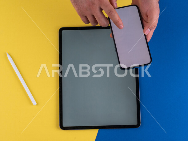 صورة مقربة ليد رجل عربي خليجي سعودي ينقر على شاشة الهاتف المحمول ، استخدام جهاز التابلت، التسويق الالكتروني للتطبيقات، التجارة الالكترونية  ، استخدام الاجهزة التقنية الحديثة في الاعمال الادارية