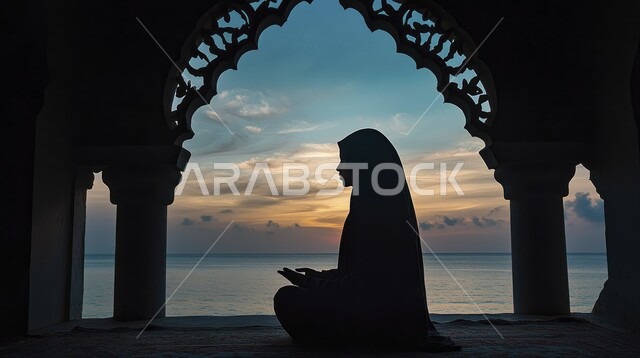 الدعاء بخشوع وتضرع, أداء الفرائض الدينية الإسلامية، مفهوم التعبد في بيوت الرحمن, العبادة والتقرب إلى الله تعالى, صورة ظلية من الجانب لامرأة عربية خليجية سعودية ترتدي الحجاب تصلي داخل المسجد وقت غروب الشمس, سالوليت