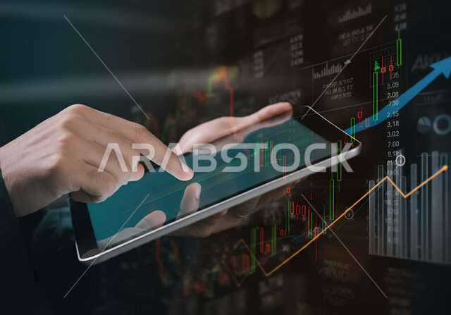 تداول العملة الرقمية، الاستثمار المالي والاقتصادي، صورة مقربة لأيدي رجل أعمال عربي خليجي سعودي يقوم بمراقبة الرسوم البيانية الاقتصادية عبر الجهاز اللوحي، متابعة ارتفاع وانخفاض الأسهم في سوق البورصة، دمج التكنولوجيا الحديثة بالعمل