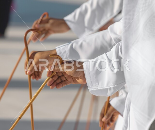 رقصات في المناسبات الوطنية والمهرجانات والأعياد في الإمارات العربية المتحدة، فعاليات واحتفالات للعرضات التراثية, فنون وعروض شعبية، صورة مقربة لأيدي فرقة عرضة عربية خليجية اماراتية يحملون عصا خشبية ويقومون بالاحتفال