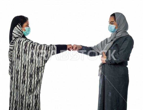 بورتريه لسيدتان عربيتان خليجيتان، ارتداء الكمامة الواقية، التصافح بقبضة اليد، اتفاق عمل بين سيدات الاعمال، صفقة ناجحة، التعاون في العمل، الالتزام باجراءات الوقاية من فايروس كورونا