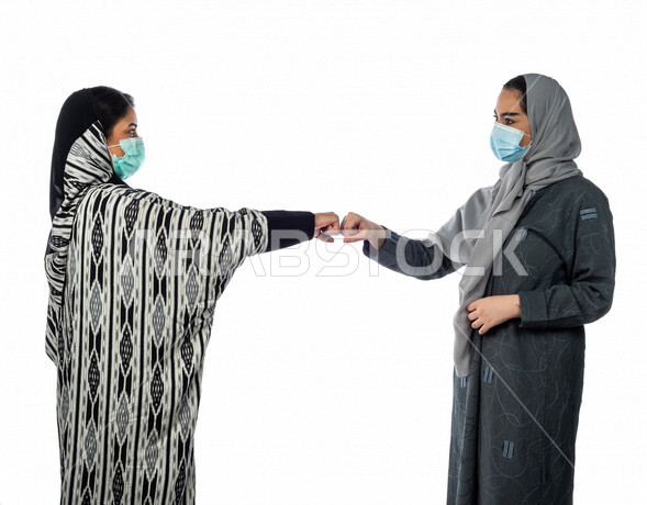 بورتريه لسيدتان عربيتان خليجيتان، ارتداء الكمامة الواقية، التصافح بقبضة اليد، اتفاق عمل بين سيدات الاعمال، صفقة ناجحة، التعاون في العمل، الالتزام باجراءات الوقاية من فايروس كورونا