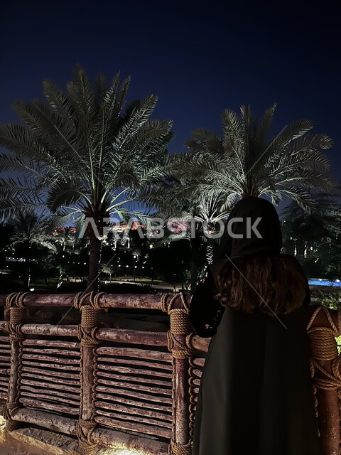 أشجار النخيل الخضراء  في الدرعية القديمة في مدينة الرياض، معالم أثرية تاريخية قديمة، صورة من الخلف لامراة عربية خليجية سعودية تنظر الى مكان ما، أماكن السياحة التراثية في السعودية، الاهتمام بزراعة النباتات الخضراء في المملكة