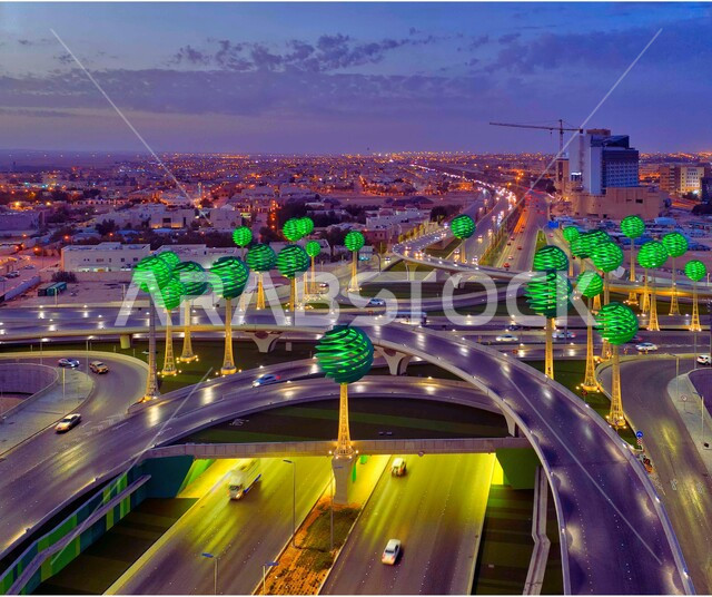 حركة المرور في شوارع وطرقات العاصمة في النهار، الفن الهندسي المعماري للمجسمات الفنية على شكل أشجار خضراء، معالم الرياض المشهورة، دوار عرقة على تقاطع طريق الملك عبد لله مع الملك خالد، تنشيط السياحة في المملكة العربية السعودية