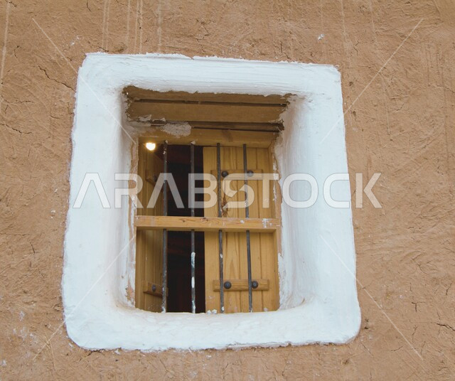 نافذة خشبية صغيرة في الجدران الطينية على الطراز التاريخي القديم، مشاريع إعادة تأهيل القرى القديمة لجذب السياح من أنحاء العالم, القرية التراثية في مدينة المجمعة التابعة لمدينة الرياض, معالم سياحية تراثية مشهورة, الحضارة والأصالة والعراقة السعودية