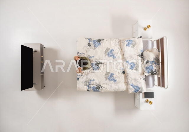 صبي عماني يرتدي نظارات الواقع الافتراضي يشاهد شيء ما بتعابير الاندماج, محاكاه العالم الخيالي، استخدام الأجهزة التكنولوجية الحديثة والمتطورة, بورتريه علوي عامودي لولد عربي خليجي سعودي يجلس على سريره في غرفه النوم, خلفية بيضاء