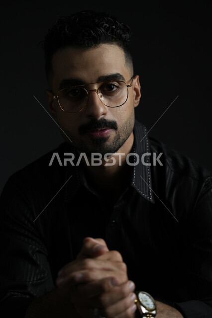 مفهوم الرجولة و الاهتمام بالمظهر الخارجي، بورتريه لشاب وسيم عربي خليجي سعودي يرتدي الزي الكاجوال ينظر إلى الكاميرا بإيماءات الثقة بالنفس، الملامح العربية الاصيلة، خلفية سوداء