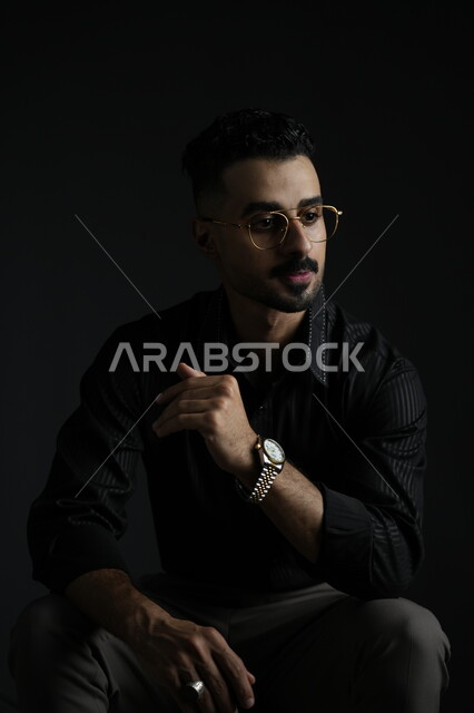 مفهوم الرجولة و الاهتمام بالمظهر الخارجي، بورتريه لشاب وسيم عربي خليجي سعودي يرتدي الزي الكاجوال ينظر إلى مكان ما بإيماءات الثقة بالنفس، الملامح العربية الاصيلة، خلفية سوداء