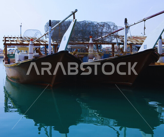 The waterfront in the State of Qatar during the day, tourist places to spend enjoyable times, a group of wooden boats in the middle of the sea on the Doha Corniche, enjoying trips and quiet sea excursions