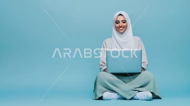 ادارة الأعمال عن بعد، استخدام الأجهزة الحديثة والمتطورة، بورتريه لامرأة عربية خليجية سعودية ترتدي العباءة والحجاب تقوم باستخدام الحاسوب المحمول، دمج التكنولوجيا بالعمل، إنجاز المهام المطلوبة عبر اللابتوب، مهن ووظائف نسائية، خلفية زرقاء