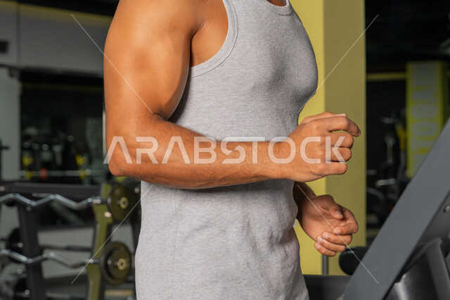 حرق الدهون وتقليل الوزن، صورة مقربة لرجل عربي خليجي إماراتي يرتدي الملابس الرياضية يقوم بالتدريب على جهاز المشي الكهربائي، أنشطة ورياضات لتقوية العضلات، شاب سعودي يركض على التريدميل، مفهوم الرشاقة واللياقة البدنية، المحافظة على أسلوب حياة صحي