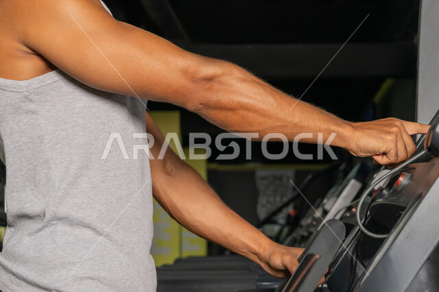 شاب سعودي يركض على التريدميل، حرق الدهون وتقليل الوزن، صورة مقربة لرجل عربي خليجي إماراتي يرتدي الملابس الرياضية يقوم بالتدريب على جهاز المشي الكهربائي، مفهوم الرشاقة واللياقة البدنية، المحافظة على أسلوب حياة صحي، أنشطة ورياضات لتقوية العضلات