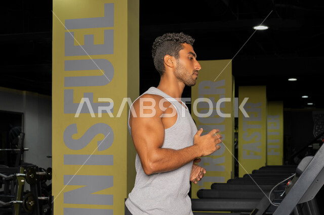 المحافظة على أسلوب حياة صحي، حرق الدهون وتقليل الوزن، رجل عربي خليجي إماراتي يرتدي الملابس الرياضية يقوم بالتدريب على جهاز المشي الكهربائي، شاب سعودي يركض على التريدميل، مفهوم الرشاقة واللياقة البدنية، أنشطة ورياضات لتقوية العضلات